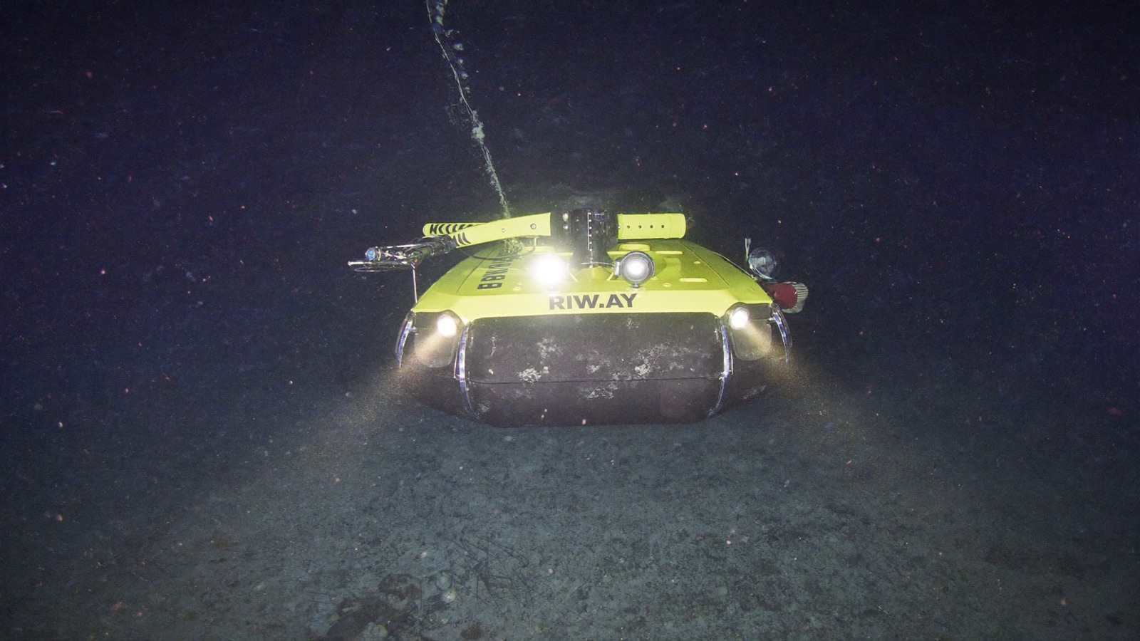 The yellow research submersible ROV Lampyra descending through dark blue water, floodlights lit, in the twilight zone.